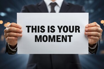 Obraz premium Man in a suit holds a motivational sign: THIS IS YOUR MOMENT
