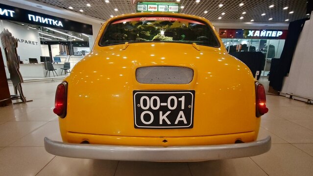 Kolpino, Russia - April 17, 2026: Yellow ZAZ 965 car displayed indoors with a visible license plate and retail environment in the background