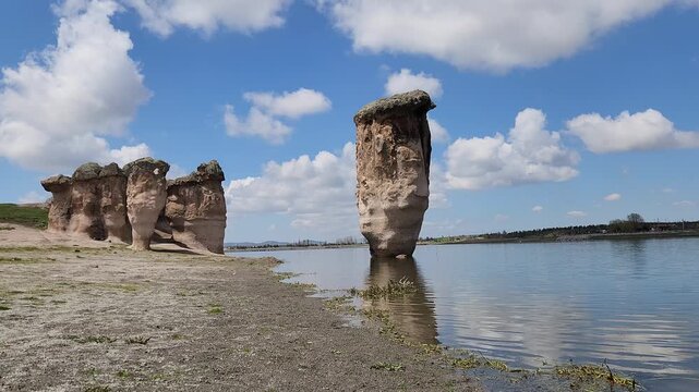 Emre Lake in spring, nestled under a vast blue sky with fluffy white clouds and surrounded by mysterious fairy chimneys