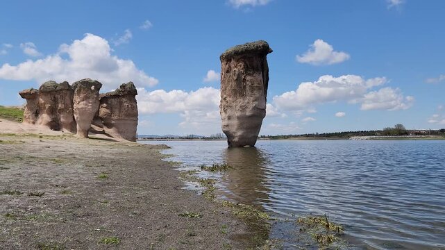Emre Lake in spring, nestled under a vast blue sky with fluffy white clouds and surrounded by mysterious fairy chimneys