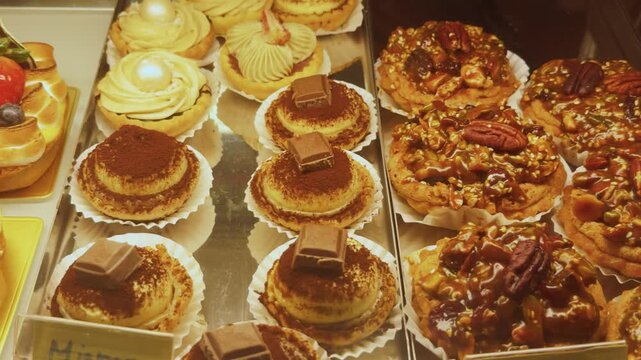 Assortment of gourmet pastries and delicate desserts, including tiramisu, fruit tarts, pecan tarts, and cream puffs, showcasing sweet indulgence in a bakery display case