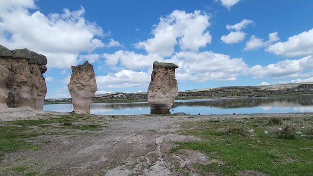 Emre Lake in spring, nestled under a vast blue sky with fluffy white clouds and surrounded by mysterious fairy chimneys