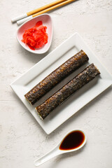 Plate with tasty maki rolls, ginger and soy sauce on light background © Pixel-Shot