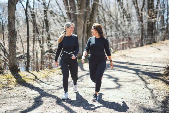 Energetic middle-aged woman jogs through a tree-lined path