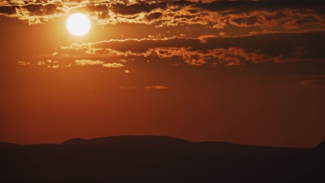 Dramatic Sunset Timelapse with Sun and Clouds Over Mountain Silhouette Zoom In