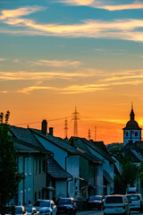 Naklejka premium Strommasten bei Sonnenuntergang über einer Stadt