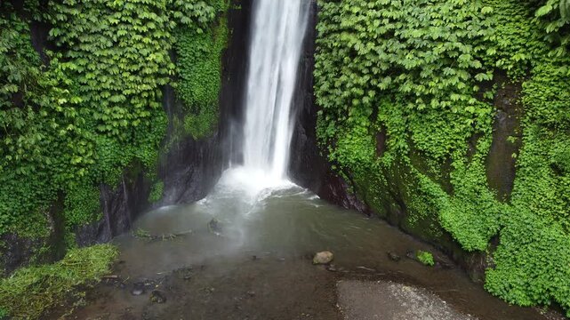 Aerial drone hovering near the base of Munduk Waterfall capturing the powerful cascade and jungle surroundings, Bali, Indonesia.