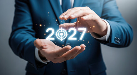 Obraz premium Businessman in suit holds glowing numbers 2027 with target symbol, representing future goals and aspirations in a professional setting