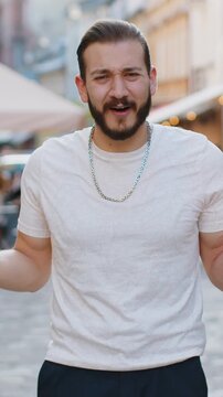 What. Why. Surprised frustrated bearded young man raising hands asking reason of failure, demonstrating disbelief irritation by troubles outdoors. Confused boy walking in urban city sunshine street