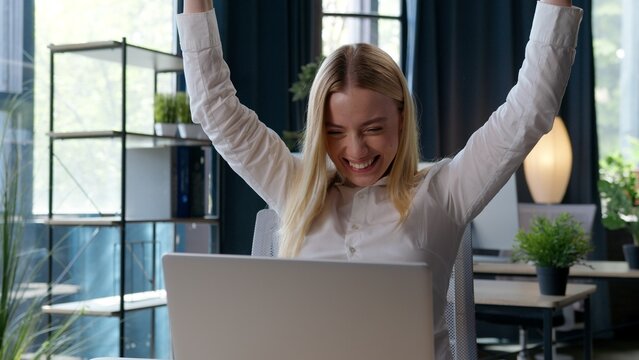 Caucasian businesswoman waiting online result winning with laptop yelling happy champion business woman successful girl female win internet bet celebrating applause cheering entusiastic glad in office