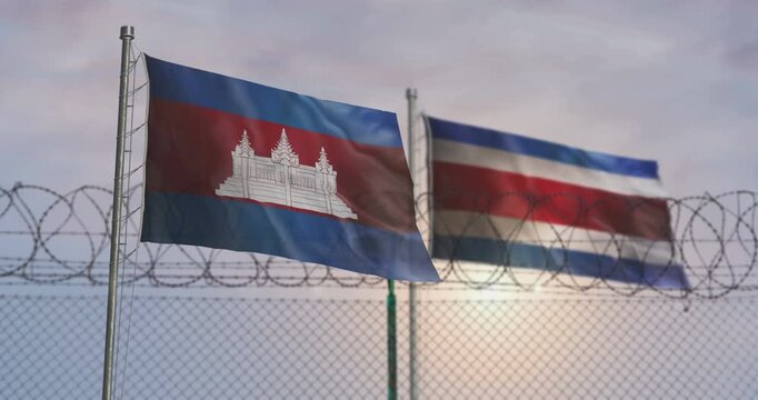Cambodia and Thailand waving flags on country border concept. Cambodian and Thai blowing banner with barbed wire fence.