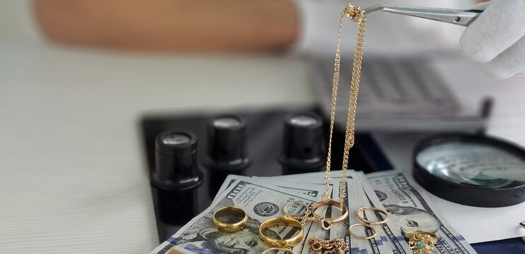 Gold and jewelry being assessed on a table with cash and tools during a valuation process in a shop