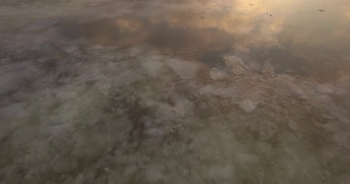 Large frozen river drone flight, chunks of ice near the bank of a large river at sunset