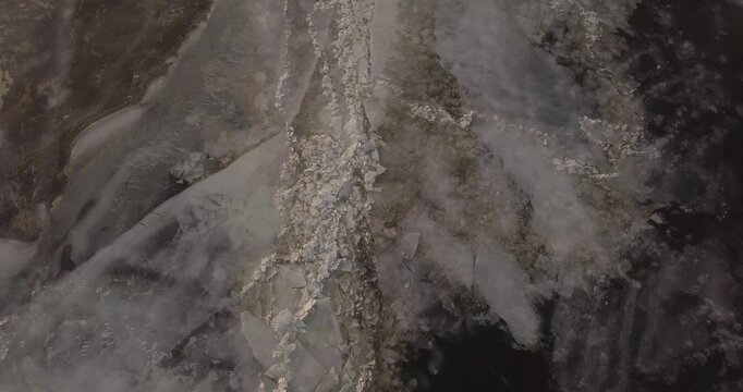 Large frozen river drone flight, chunks of ice near the bank of a large river