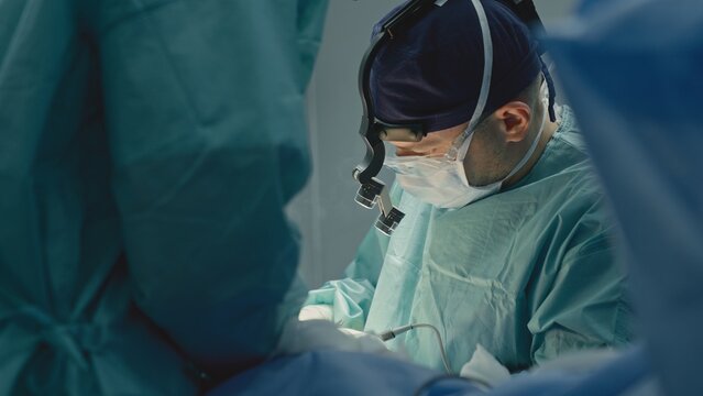 Two medics in operation room working together skilled doctor man surgeon physician medic work busy with operation operating patient with nurse intern help cooperate at microsurgery innovative medicine