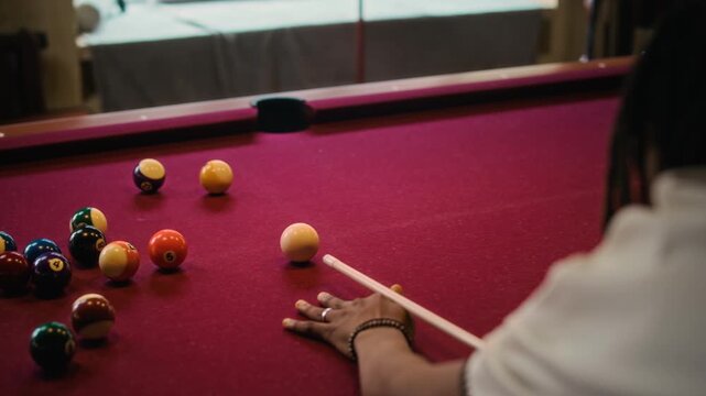 Over shoulder shot of African American man lining up cue with ball but missing shot during billiards game on red felt table at pool club, slow motion
