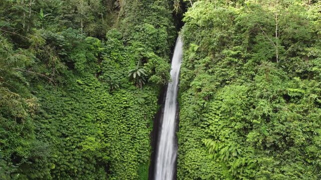 Aerial drone hovering in front of the dramatic water drop of Munduk Waterfall, Bali, Indonesia.