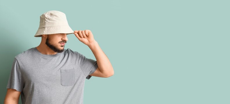 Handsome young man in stylish bucket hat on grey background with space for text
