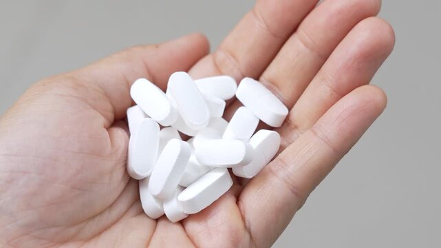 close up woman hand holding a medicine, with pours the pills out of the yellow orange medicine bottle. Stop drug use Taking Medication Caring for the health care medical concept.