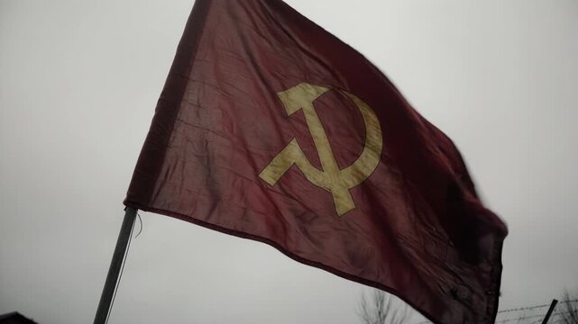 Soviet flag waving behind a barbed wire fence. Historical footage of a military camp with the USSR symbol. Second World War and Eastern Front theme