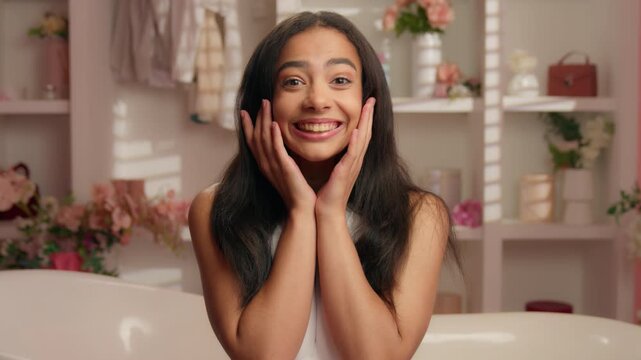 Beautiful Hispanic woman shocked looking at camera posing in pink bathroom near bathtub in hotel home Latina Arabian girl ethnic female amazed surprised open mouth astonishment in candy glamour bath