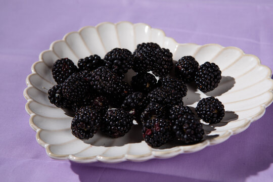 blackberries in heart plate on lilac cloth table top black blackberries