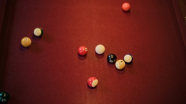 Top view shot of cue ball hitting rack on red baize billiards table while starting pool game at snooker hall