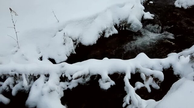 Drone view of Oulanka National Park Kuusamo Finland showing dark flowing creek cutting through deep snow covered forest creating peaceful winter nature scene