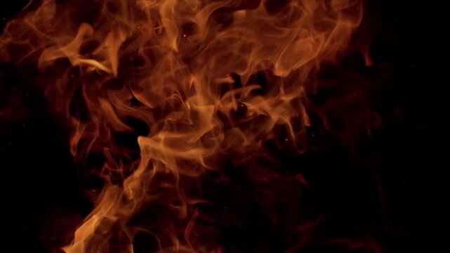 Extreme close-up macro shot of intense blazing fire with glowing orange and red flames dancing and flickering against a pure black background.