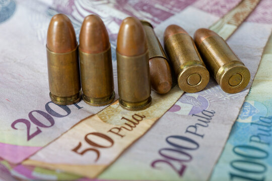 Botswana Pula Banknotes with Standing 9mm Pistol Ammunition lying scattered across the currency.