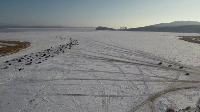Where the river meets bay, the frozen waters attract dozens of winter anglers. Cars are lined up on the ice, and some drive far across the bay, carving multiple tracks into the frozen surface.