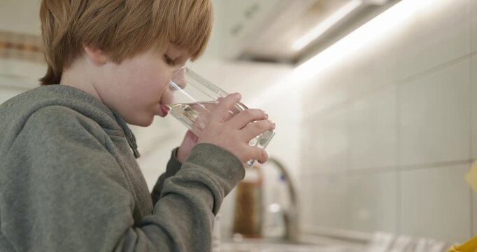 Kid Boy Drinks Glass of Water in Kitchen. 4K 10-bit