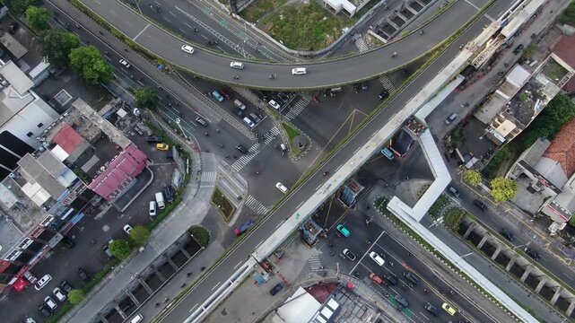 Jakarta, Indonesia - April 26th 2026: Aerial Top-Down View of Complex City Intersection and Flyover. High Angle Drone Shot of Urban Traffic with Construction of Elevated Train Track