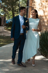 Fototapeta premium Happy bride and groom walking and embracing outdoors in romantic wedding setting