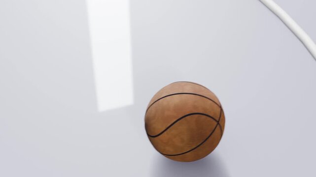 Dropping basketball passing under curved white arc on arena court, bouncing, spinning, settling