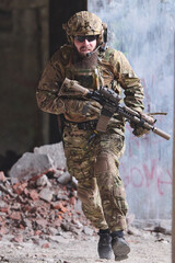 Obraz premium Bearded Soldier In Tactical Gear Running With Rifle Through Urban Ruins During Military Operation