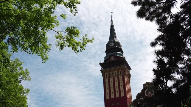 Historic City Hall tower rises above green trees in Subotica under a bright spring sky. Concept of civic heritage, urban identity, and architectural tourism