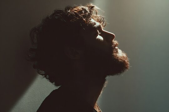 Bearded man profile in soft light, a contemplative silhouette looking upwards with a textured beard