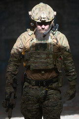 Obraz premium Bearded Soldier Wearing Camouflage Tactical Gear And Helmet Holding Rifle During Urban Operation