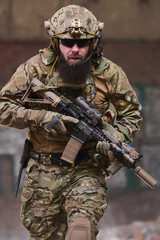 Fototapeta premium Bearded Soldier In Tactical Gear With Rifle Wearing Camouflage Helmet And Night Vision Mount