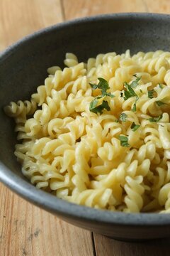 close up a bowl of fusilli pasta on a wooden table