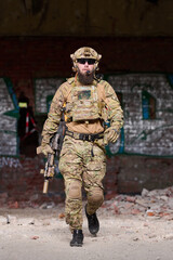 Obraz premium Armed Soldier in Tactical Gear Walking Through Urban Ruins With Rifle and Helmet