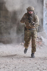 Obraz premium Armed Soldier In Camouflage Running With Rifle During Urban Combat Training In Dusty Ruins