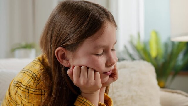 Thoughtful sad Caucasian child little girl kid daughter upset lonely bored stress boring at home thinking family custody problem think on couch childhood trouble childcare pediatric psychology help