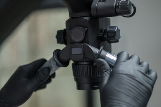 Close up of dentist hands in black gloves adjusting microscope