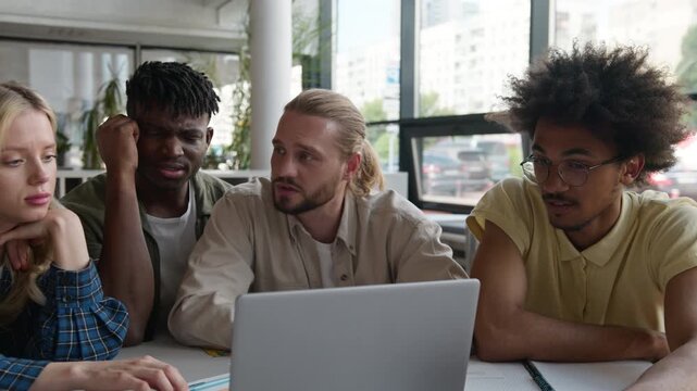 Group of five troubled multiethnic students friends with laptop studying girls guys discuss internet web homework task fail together concentrated talking looking in computer study learning in college