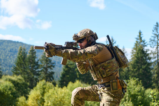 Tactical Soldier Aiming Rifle In Woodland Training Exercise With Full Combat Gear And Optics