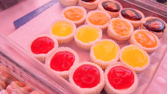 Colorful fruit jelly tarts and cupcakes at a local street market stall