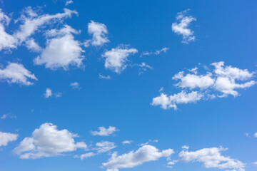 Obraz premium A vast bright blue sky filled with scattered white fluffy cumulus clouds on a clear sunny day, creating a peaceful and serene natural atmosphere for various backgrounds.
