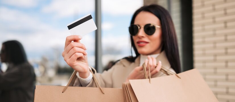 Stylish woman holding credit card and shopping bags after a successful retail purchase